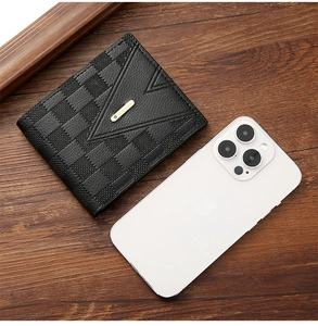 Detail of black checkerboard leather wallet with gold logo on a wooden surface