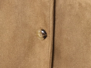 Dettaglio ravvicinato della texture in pelle scamosciata e bottone a tartaruga