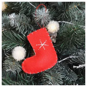 Close-up of red felt Christmas stocking ornament with white snowflake on green tree