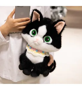Close-up of cute tuxedo cat plush with colorful crochet collar held in hands