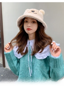 Detail of plush bear ear bucket hat paired with a green cardigan and white ruffled collar