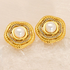 Dettaglio di orecchini vintage con perle dorate, strass e trama in metallo intrecciato