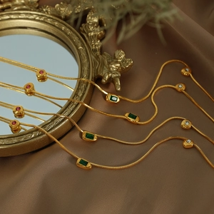 French vintage necklace with green zircon pendant on gold chain over satin background