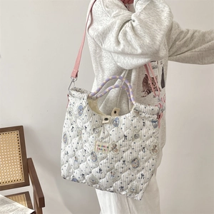 Détail du sac matelassé à rayures bleues avec motif ours et poignées tissées violettes