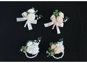 Close-up of white and champagne silk rose boutonnieres and pearl wrist corsages