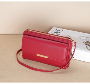 Detail view of red leather crossbody wallet with gold metal trim and double zippers