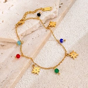 Detail of gold stainless steel bracelet with multi-color beads and star charms on stone