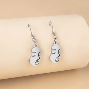 Modern abstract face earrings in polished stainless steel on neutral background