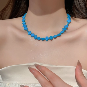 Detail of blue diamond-shaped beaded necklace on model neck for beach style