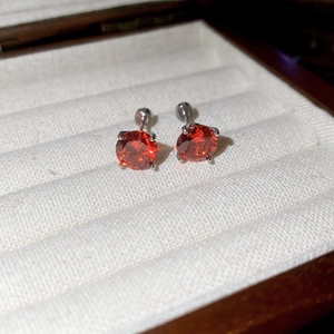 Detailed shot of sparkling round red zircon earrings with secure threaded screw backs