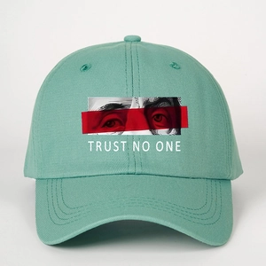 Detail of teal cotton baseball cap featuring TRUST NO ONE text and eye graphic