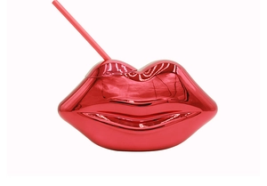 Macro shot of red disco lip-shaped cup with shiny metallic finish and matching straw