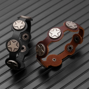 Detail of black and brown vintage leather bracelets featuring silver star metal badges