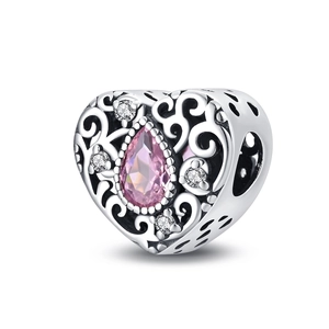 Detailed view of silver-plated heart charm with pink teardrop stone and intricate cutouts