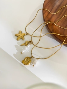 Detail of gold seashell, starfish, and freshwater pearl necklace with hammered texture