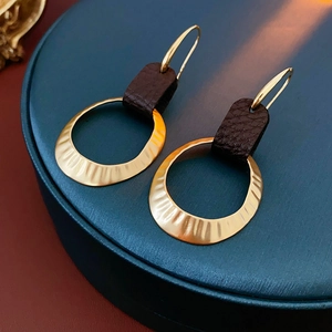 Macro shot of gold hammered metal hoops with dark brown leather drop earrings