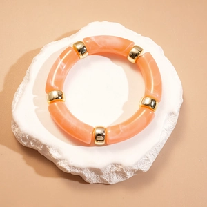 Détail de segments en résine marbrée orange avec perles en métal doré sur pierre