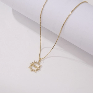 Detailed view of gold MOM sunburst pendant necklace with cubic zirconia on a white stand