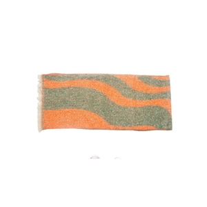 Detail of orange and green wavy pattern on plush boucle yarn scarf with tassel edges