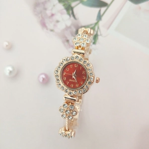 Detail of flower-shaped golden quartz watch with red dial and sparkling rhinestones