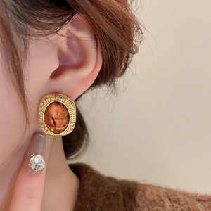 Detail of elegant gold-plated resin earring on model with amber oval stone accents
