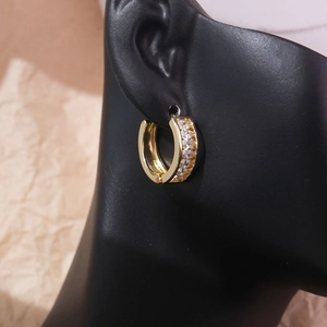 Detailed close-up of golden brass geometric C-shaped earrings with sparkling cubic zirconia