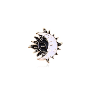Detail of celestial sun and moon enamel brooch with gold metallic edges and black and white colors
