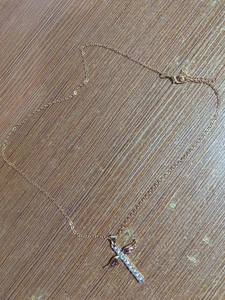 Detailopname van gouden kruishanger met fonkelende zirkonia en vleugelmotief