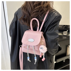Dettaglio zaino in pelle rosa con logo in metallo argento e ciondolo a forma di mostro peloso