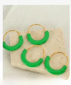 Close-up of four green enamel crescent earrings with gold plating on stone surface