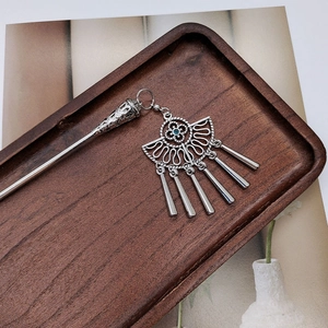 Detail of vintage silver hair stick with blue bead and tassel on wooden tray