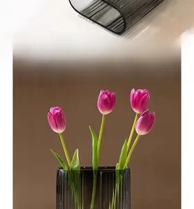 Close-up of ribbed gray glass vase with minimalist U-shaped design and tulip decor
