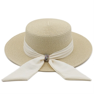 Detail of light beige straw hat with white chiffon ribbon and colorful rhinestone buckle