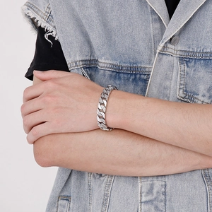 Détail du bracelet gourmette argenté pour homme serti de diamants sur fond gris clair