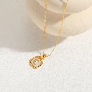 Detailed macro of a square shell pendant with a diamond crescent moon on a gold chain