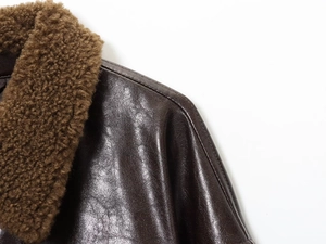 Detailed macro view of dark brown leather jacket featuring a plush faux fur collar