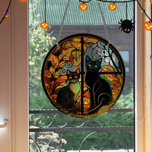 Detail of round acrylic suncatcher with two black cats and autumn leaves hanging on chain