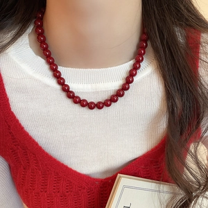 Close-up of a minimalist red glass beaded necklace worn by a model for a chic look