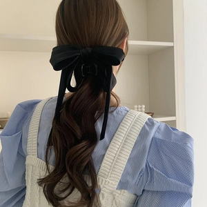 Detail of large black silk bow hair clip worn by model for elegant style