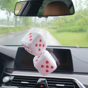 Close-up of white plush dice with red hearts hanging on a car rearview mirror
