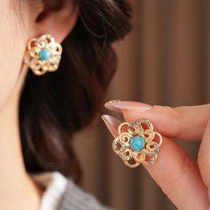 Detailed macro view of vintage gold hollow flower earrings with turquoise stones and crystals
