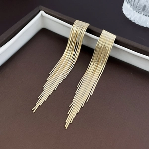 Detail shot of elegant long gold tassel earrings with multiple fine metal chains