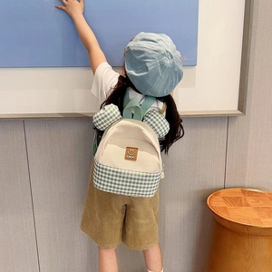 Kids fashion backpack with green plaid pattern and cute ear design on a model