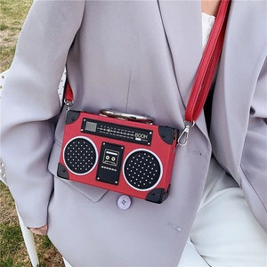 Retro red radio shaped crossbody bag with shoulder strap worn over a grey blazer