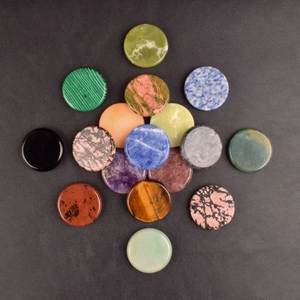 Polished flat round natural healing stones set in cross pattern on leather background