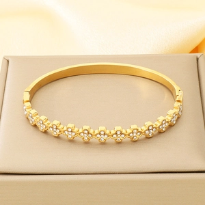 Detailed macro view of gold-plated bangle with sparkling white zircon clover patterns