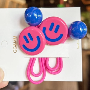 Detail of pink smiley face hair ties with blue beads on white display card