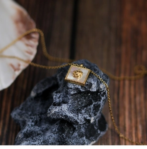Detail of 18K gold-plated rose flower pendant with white shell inlay on black stone