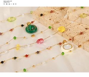 Détail de colliers en acier titane avec perles en pierre naturelle sur tissu de soie