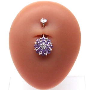 Close-up of silver navel ring with purple flower charm and crystals on a belly model